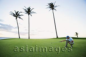 Asia Images Group - man squatting on golf course, judging angle