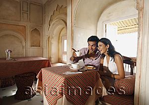 Asia Images Group - couple sitting at table, man pointing out