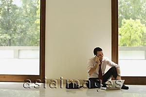 Asia Images Group - businessman on phone, sitting on floor with computer