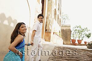 Asia Images Group - young couple holding hands walking up a slope, woman in sari