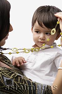 Asia Images Group - baby in mother's arms, playing with necklace