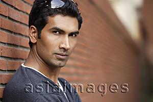 Asia Images Group - man standing against brick wall