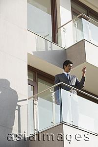 Asia Images Group - businessman with mobile phone standing on balcony