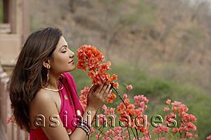 Asia Images Group - young woman in sari, smelling flowers