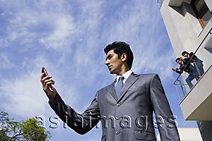 Asia Images Group - businessman with phone, associates on balcony above