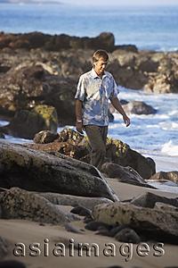 Asia Images Group - mature man walking along rocky beach