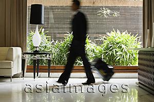 Asia Images Group - businessman walking through hotel lobby