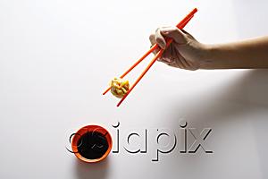 AsiaPix - hand holding dimsum between orange chopsticks