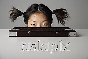 AsiaPix - Young woman peering above table with abacus.