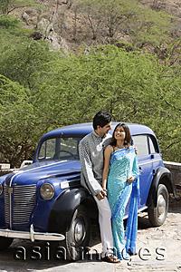 Asia Images Group - young couple looking at each other in front of blue antique car