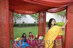Asia Images Group - three young women wearing saris, in red tent