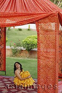 Asia Images Group - young woman in yellow sari, sitting in red tent