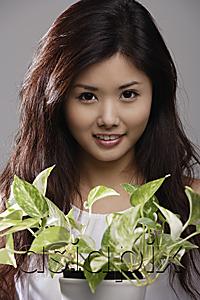 AsiaPix - Head shot of Chinese woman holding green plant