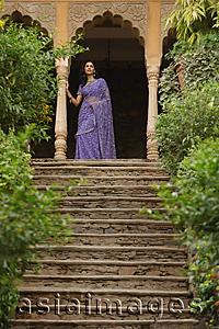 Asia Images Group - young woman in sari, standing at top of stairs