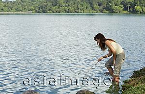 Asia Images Group - Young woman playing with stick in lake