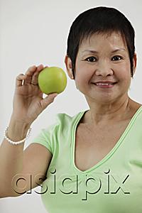 AsiaPix - Mature Chinese woman holding green apple and smiling