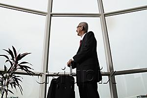 AsiaPix - mature man looking out the window and holding luggage