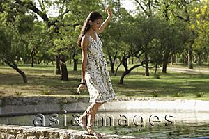Asia Images Group - Teen girl walking on wall by lake