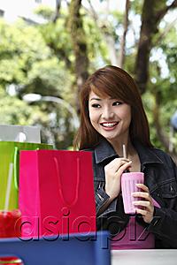 AsiaPix - Young woman sitting outside a holding drink