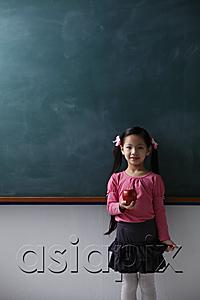 AsiaPix - Young girl holding red apple in front of chalk board