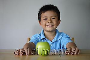 Asia Images Group - Boy sitting at table with green apple