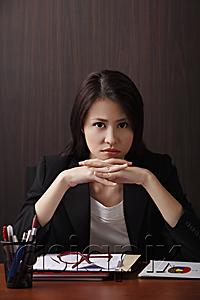 AsiaPix - Woman sitting at desk with head on hands frowning