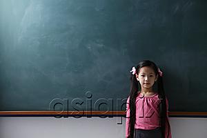 AsiaPix - Young girl with pony tails standing in front of chalkboard