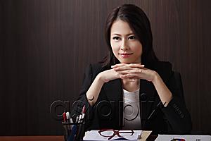 AsiaPix - Woman sitting at desk with hands folded