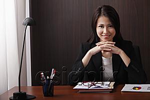 AsiaPix - woman sitting at desk with folded hands smiling