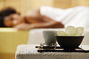 Mind Body Soul - Spa treatment with flower in bowl with woman in background