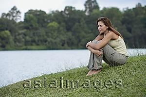 Asia Images Group - Woman hugging her knees by lake
