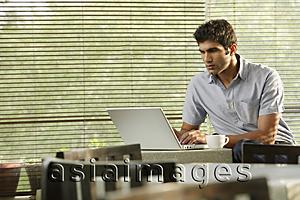 Asia Images Group - young man at laptop, with coffee