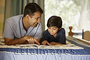 Asia Images Group - father and son reading book on bed