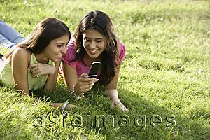Asia Images Group - two teen girls in park, looking at text messages
