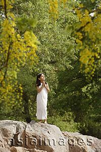 Asia Images Group - girl in white sari, standing in yoga pose on rock