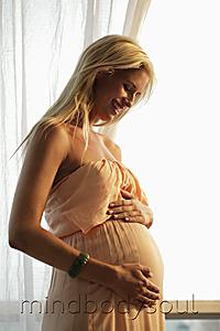 Mind Body Soul - blond pregnant woman looking at her belly and smiling