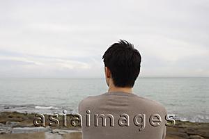 Asia Images Group - Man sitting seaside looking out to ocean