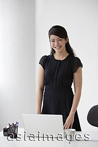 Asia Images Group - Young woman standing at desk