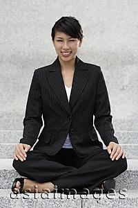 Asia Images Group - Businesswoman sitting crossed-legged outside