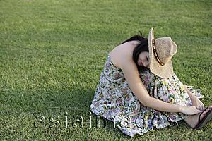 Asia Images Group - Young woman sitting on grass with head resting on knees