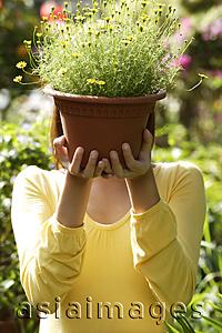 Asia Images Group - Young woman at nursery, holding potted plant