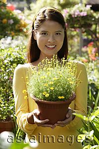 Asia Images Group - Young woman at nursery, holding potted plant