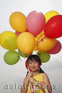Asia Images Group - Girl smiling at camera holding balloons.