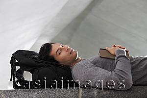 Asia Images Group - man laying down head resting on back pack