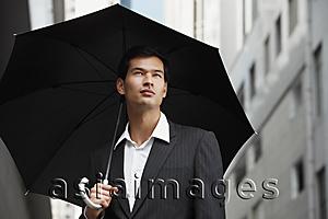 Asia Images Group - businessman holding umbrella, looking up