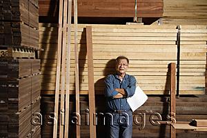 Asia Images Group - Mature man leaning against a stack of lumber.
