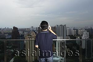 Asia Images Group - Young man listening to music and looking at view
