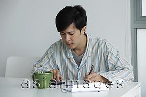 Asia Images Group - Young man working on bills at home