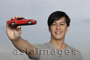 Asia Images Group - Young man holding up red toy car