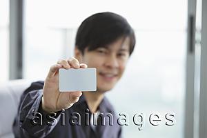 Asia Images Group - Young man holding up a credit card